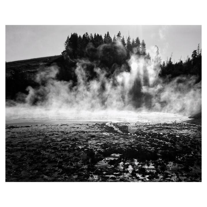 Steam rises from a muddy landscape with a forest in the background.