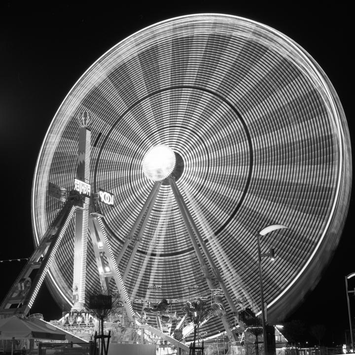 A long exposure captures the motion of a ferris wheel at night.