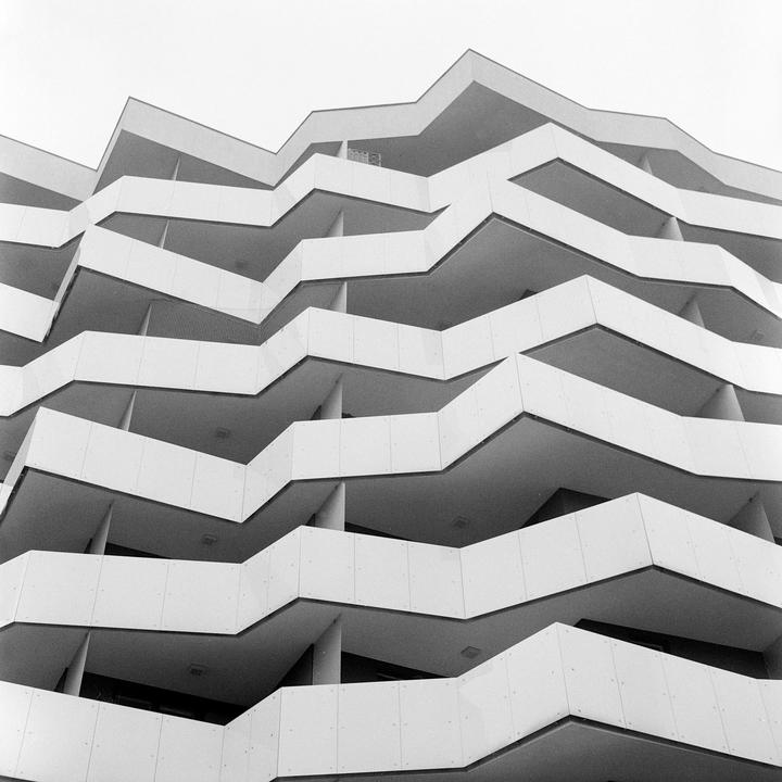 A low-angle view shows the zig-zagging balconies of a modern building.