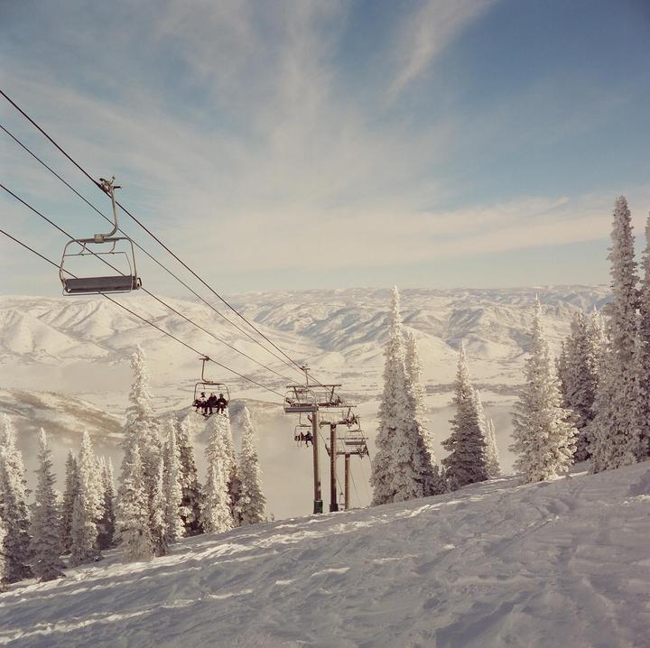 A ski lift carries people over a snowy mountain landscape with frosted trees.