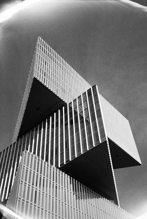 A low-angle view shows the geometric facade of a modern building against a clear sky.