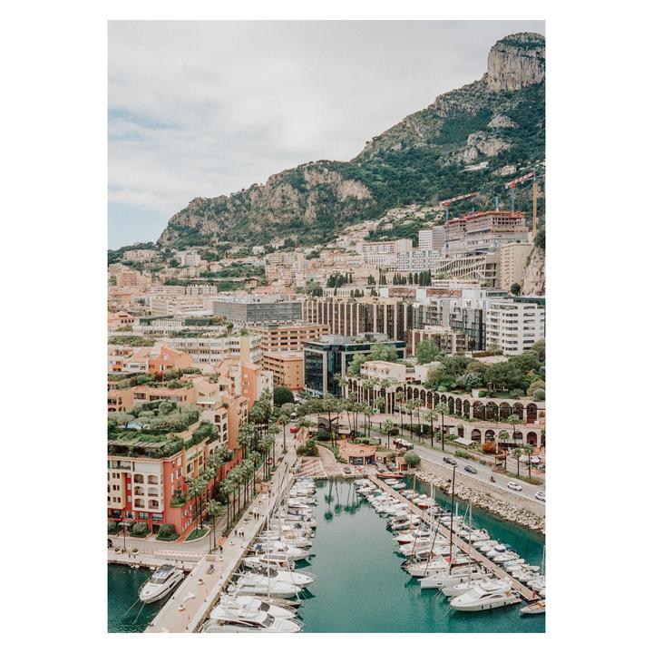 A harbor filled with boats is nestled at the base of a mountain covered with buildings.