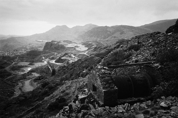 An abandoned slate quarry with mountains in the background is visible from a high vantage point.