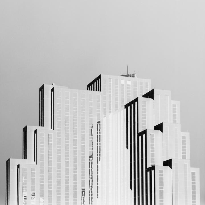 A tall, stepped building with many windows is shown against a plain sky.