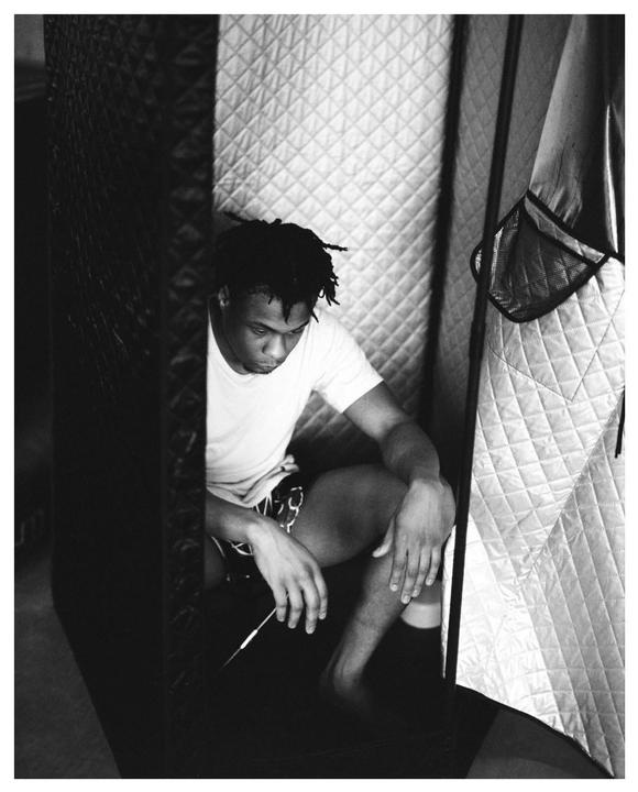 A man sits inside a portable sauna, looking down at his hands.