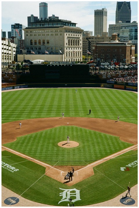 A baseball game is underway in a stadium with a city skyline in the background.