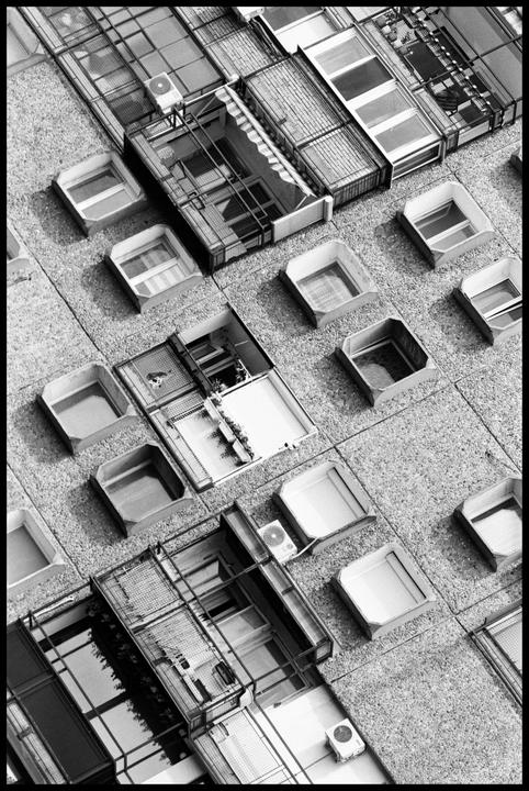 An aerial view shows the rooftops of buildings with skylights and air conditioning units.