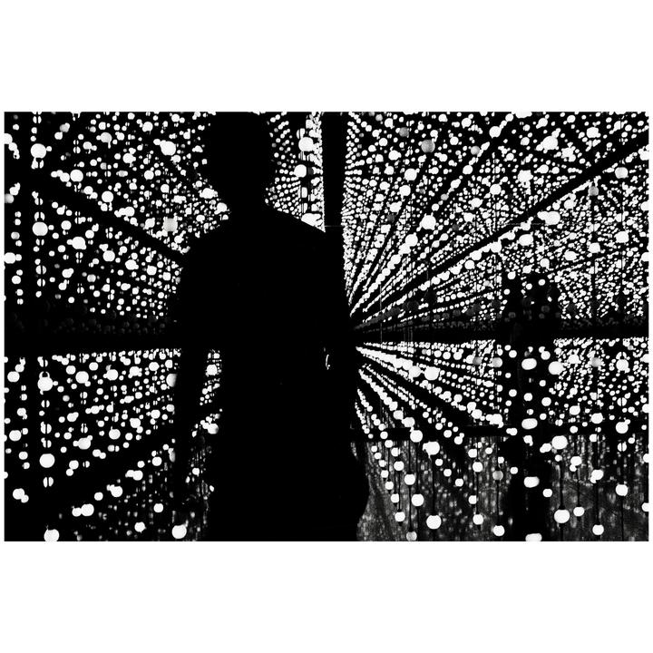 A silhouette of a man stands in a room filled with glowing orbs.