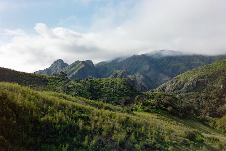 Clouds hang low over the green, rolling hills of the Santa Monica Mountains.