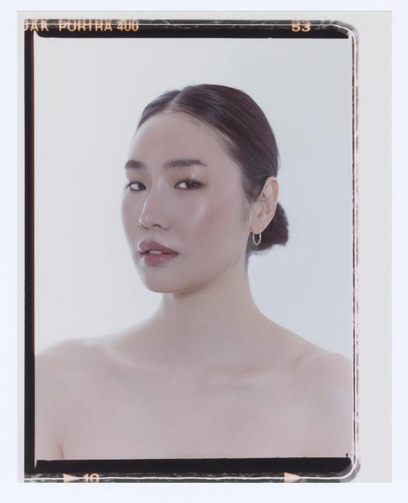 A woman with her hair pulled back looks directly at the viewer.