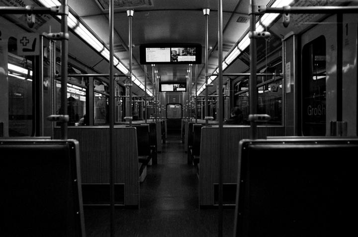 The interior of a subway car is visible, with rows of empty seats and overhead lights.