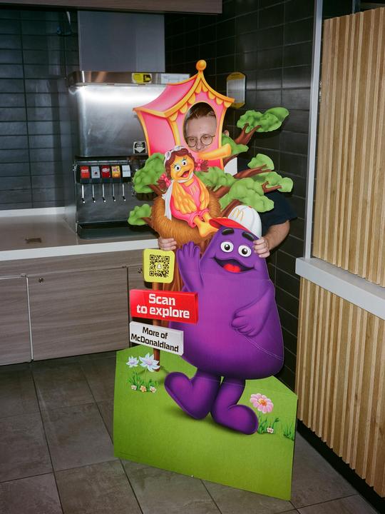 A man poses behind a McDonald's standee with his face in a cutout.