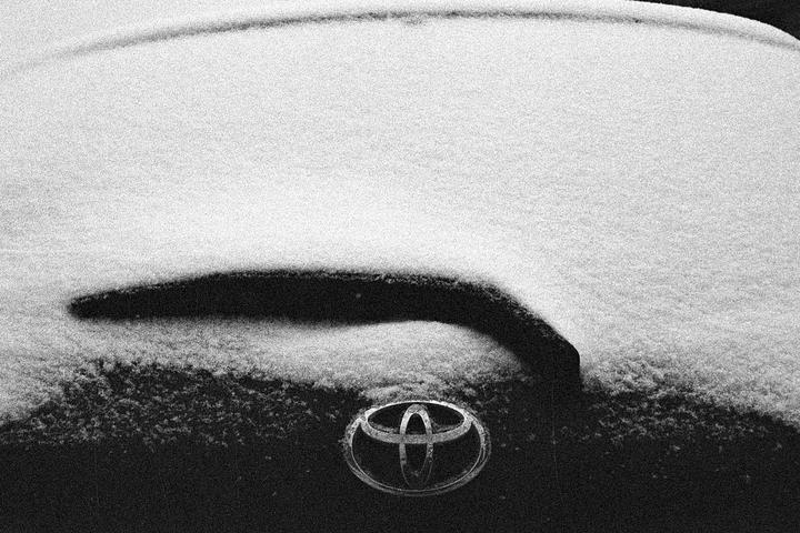 A car hood covered in snow with a Toyota emblem visible.