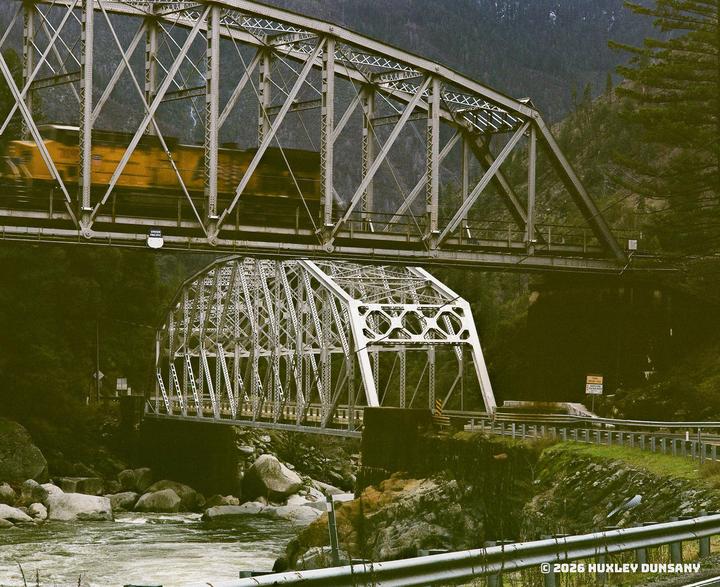 A locomotive crossing a bridge over another bridge over a river. Shot with a Mamiya RB67 + 90mm lens + Kodak Gold 400 film