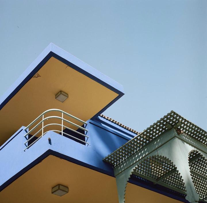 Two colorful building facades are visible against a clear sky.