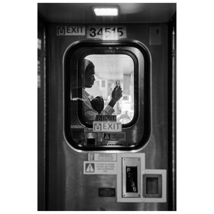 A man looks at his phone through a train window.