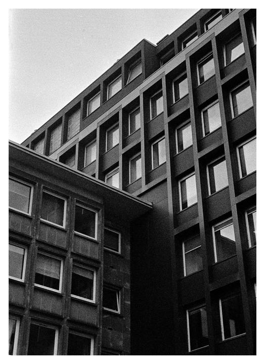 Two buildings with many windows are visible from a low angle.