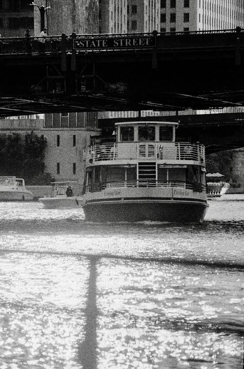 A large boat named Evening Star cruises on a river under a bridge with a "State Street" sign.