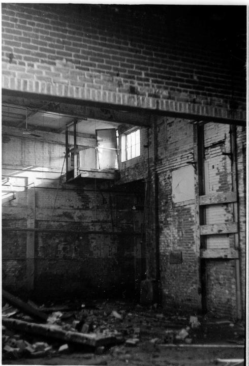 A ruined brick building interior shows debris on the floor and light coming through a window.