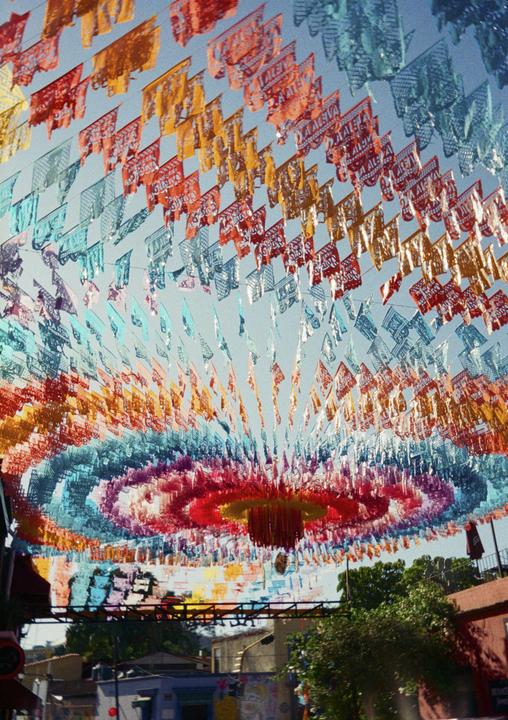 Colorful papel picado banners are strung across a street, creating a vibrant canopy.