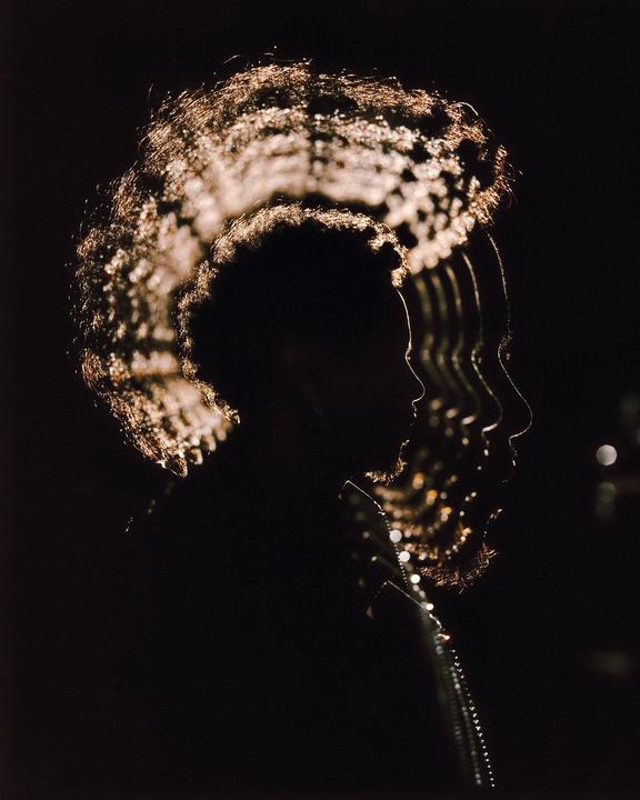 A man's profile is visible in multiple exposures with light reflecting off his hair and beard.