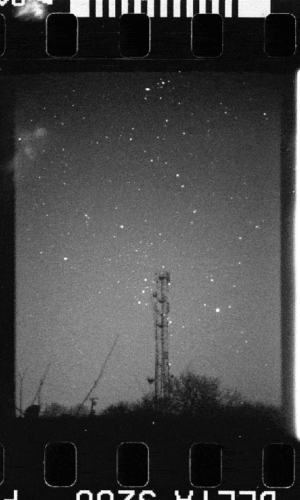 A tall communication tower stands against a night sky filled with numerous stars.
