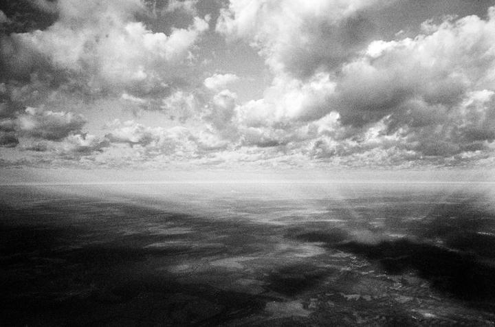 An aerial landscape shows a vast expanse of land under a cloudy sky.