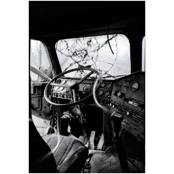 The interior of a truck cab with a shattered windshield is visible.
