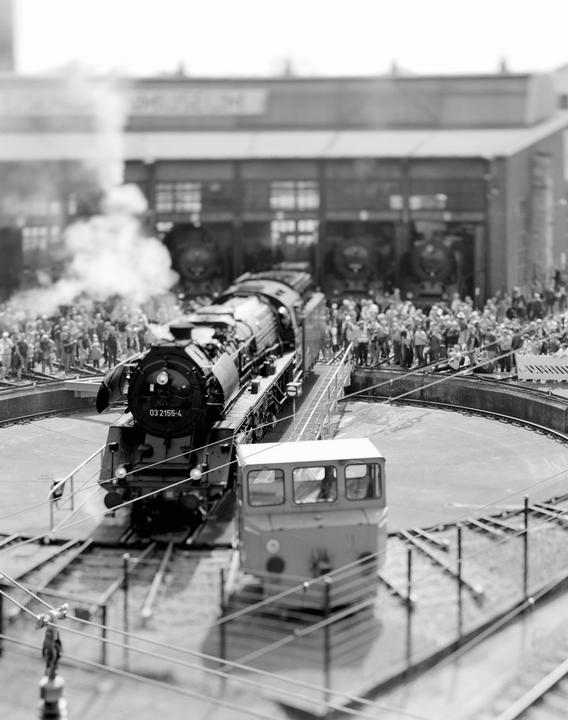 A steam locomotive is on a turntable with a crowd of people watching in the background.