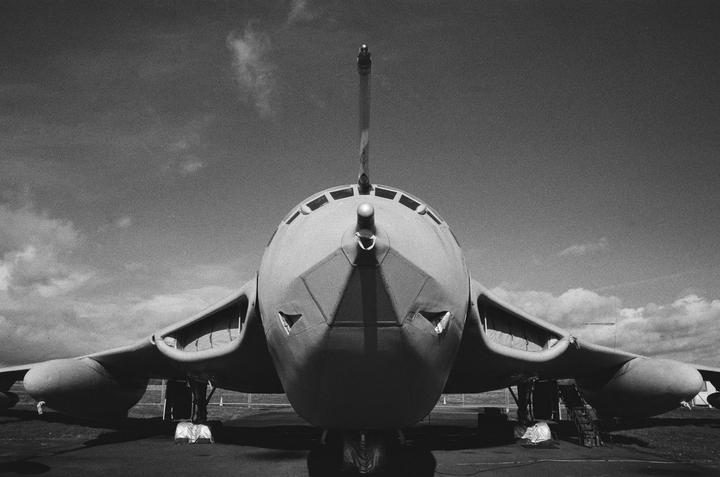 A large bomber aircraft is viewed head-on from a low angle against a cloudy sky.