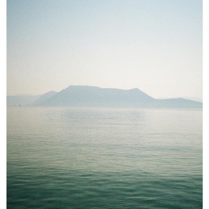 A hazy mountain range rises above a calm body of water.
