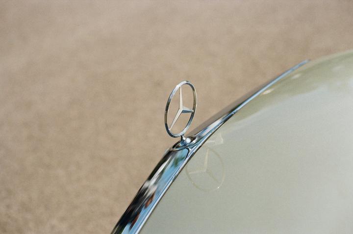 A Mercedes-Benz hood ornament is visible on the front of a car.