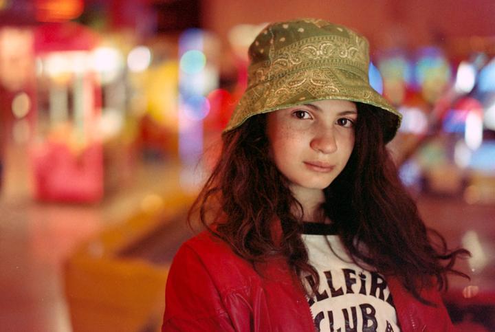 Daughter at the arcade games (and lit by one). [Nikon F5 + Zeiss Milvus 50mm f/1.4 + Ferrania Solaris FG100 Plus (expired 2009)].