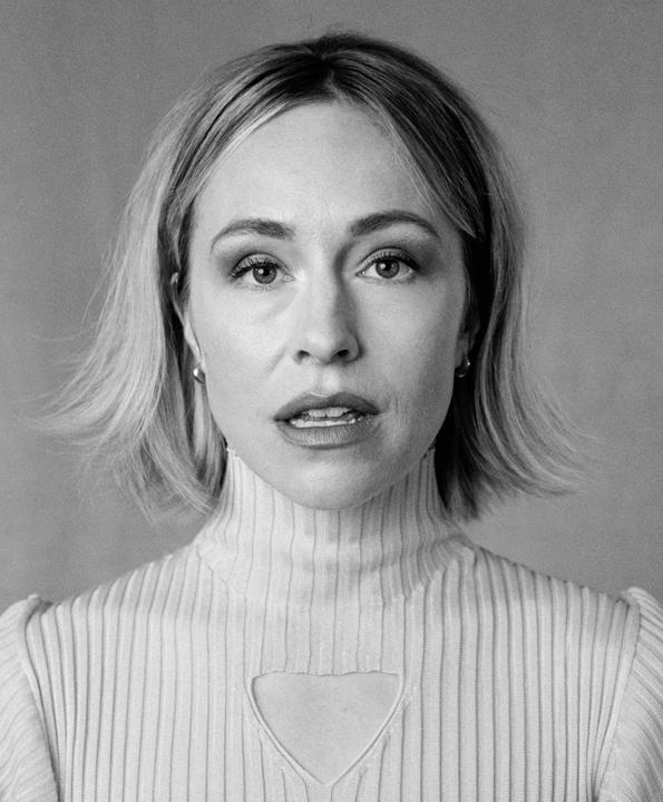 A woman with short hair and a turtleneck sweater looks directly at the viewer.