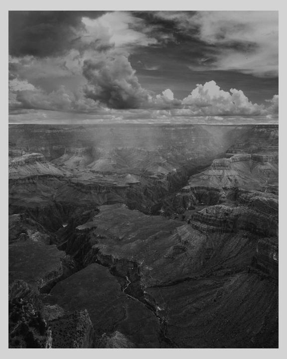 A vast canyon landscape is visible under a cloudy sky with shafts of light.