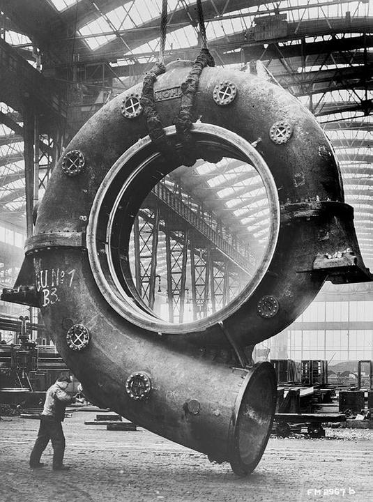 A man works on a large piece of machinery in a factory.