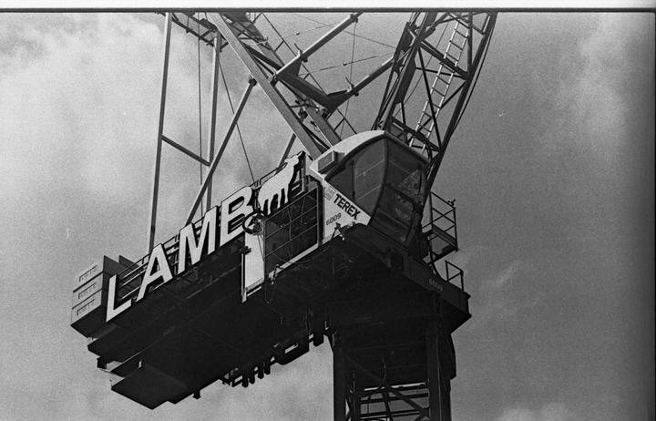 A large crane with the word "LAMB" written on its side is shown against a cloudy sky.