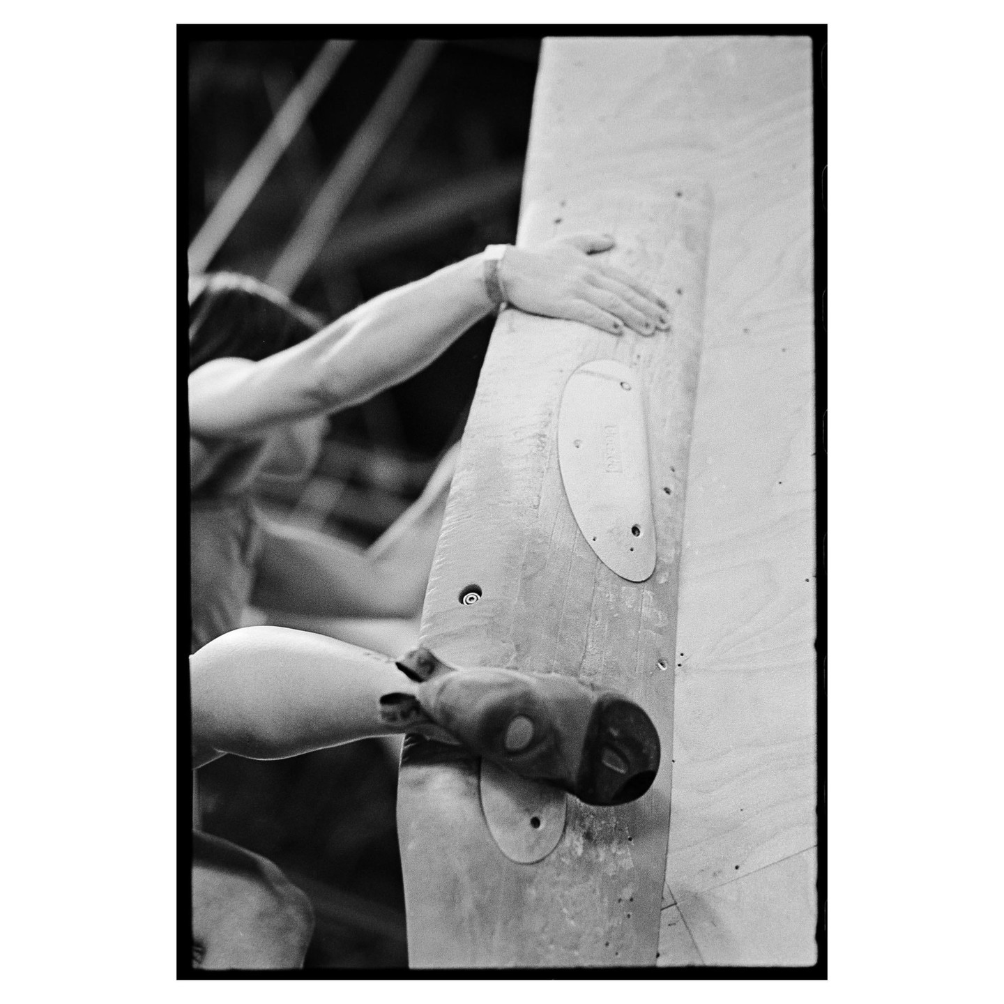 A person is climbing a wooden wall with climbing holds.