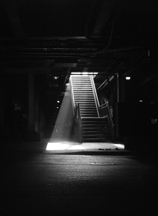 A beam of light illuminates a dark underground staircase.