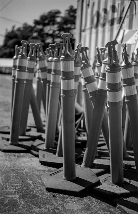 A group of traffic delineators with reflective bands stands on a paved surface.