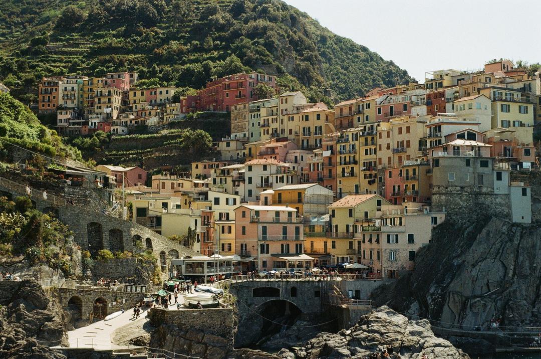 A colorful village is built into a steep hillside overlooking the water.