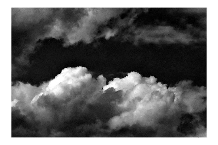 A black and white image shows clouds against a dark sky.