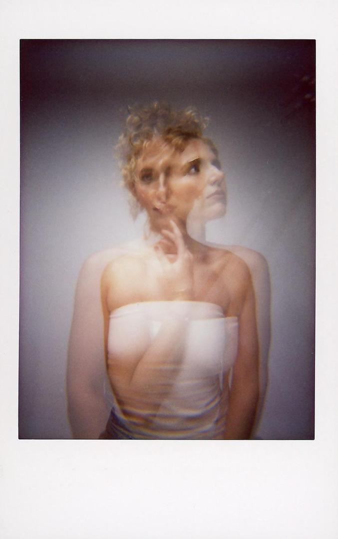 A woman with curly hair is captured in a double exposure, creating a blurred and layered effect.