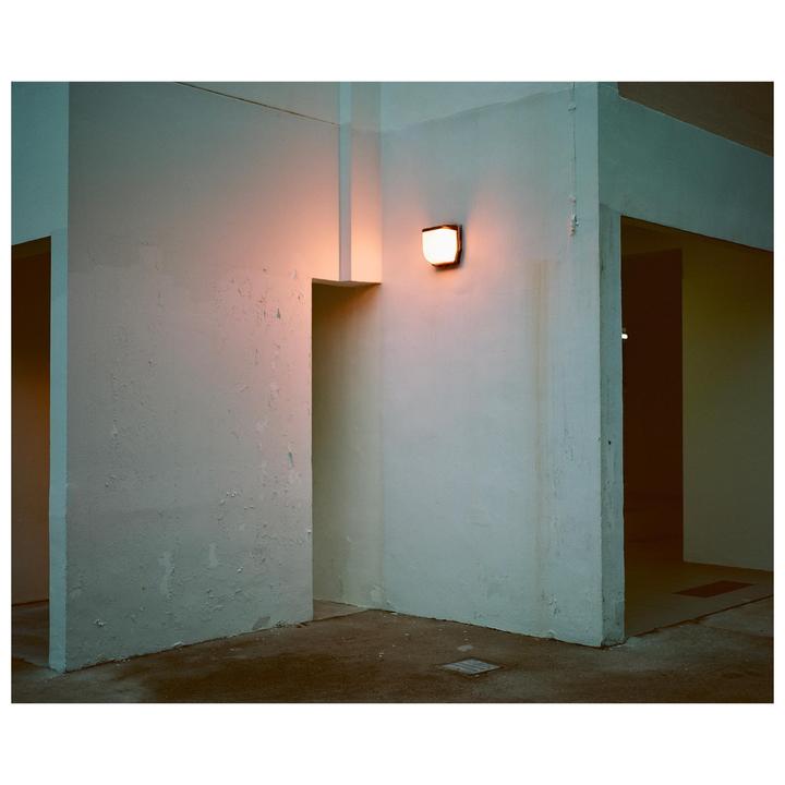 A single light illuminates a corner of a corridor with multiple doorways.