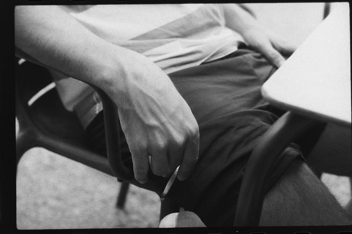 A man sits in a chair with a cigarette between his fingers.