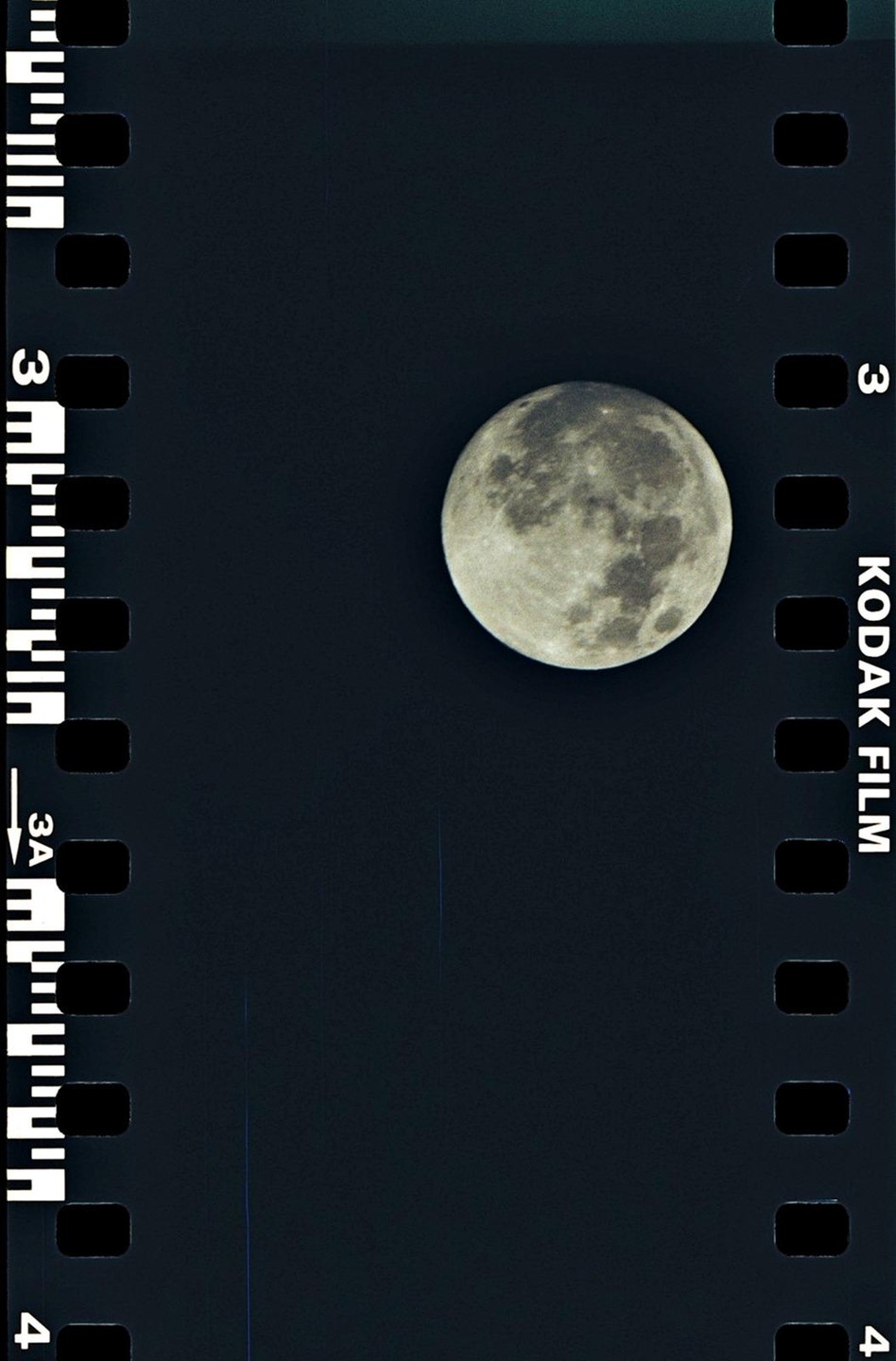 A full moon is visible against a dark sky, framed by the sprockets and text of a film strip.