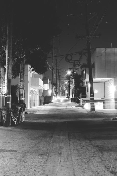 A long exposure shot of a street at night shows light trails from vehicles and streetlights illuminating the scene.