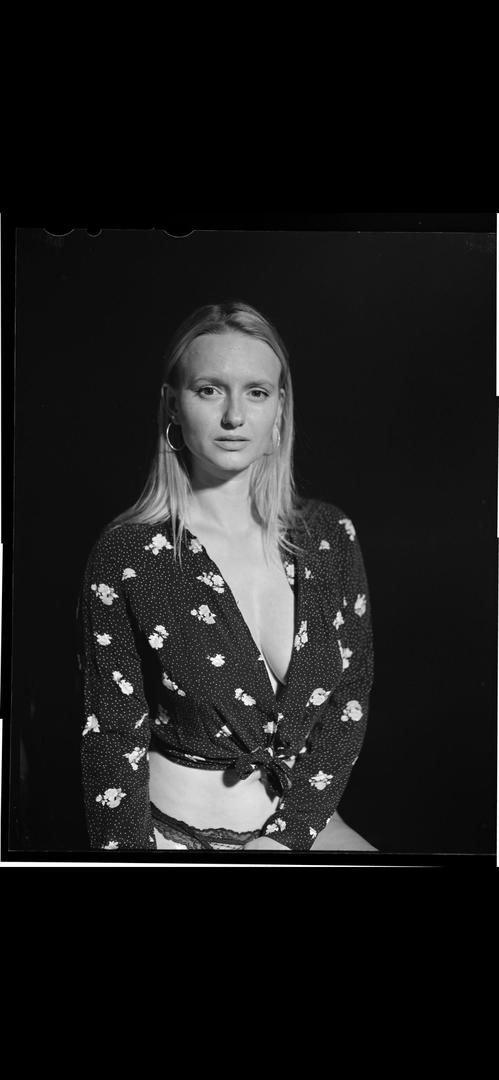 A woman with long hair and hoop earrings wears a floral top and lace underwear.