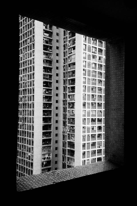 A tall building with many windows is framed by a dark window.