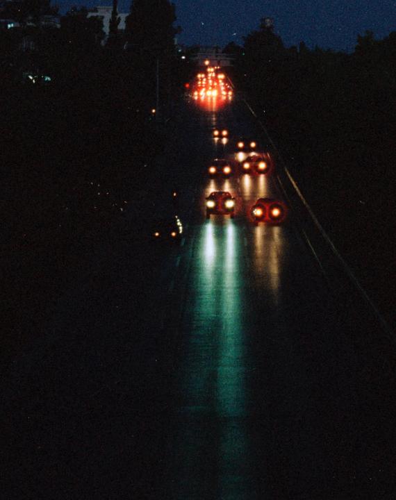 Headlights and taillights illuminate a dark road at night.